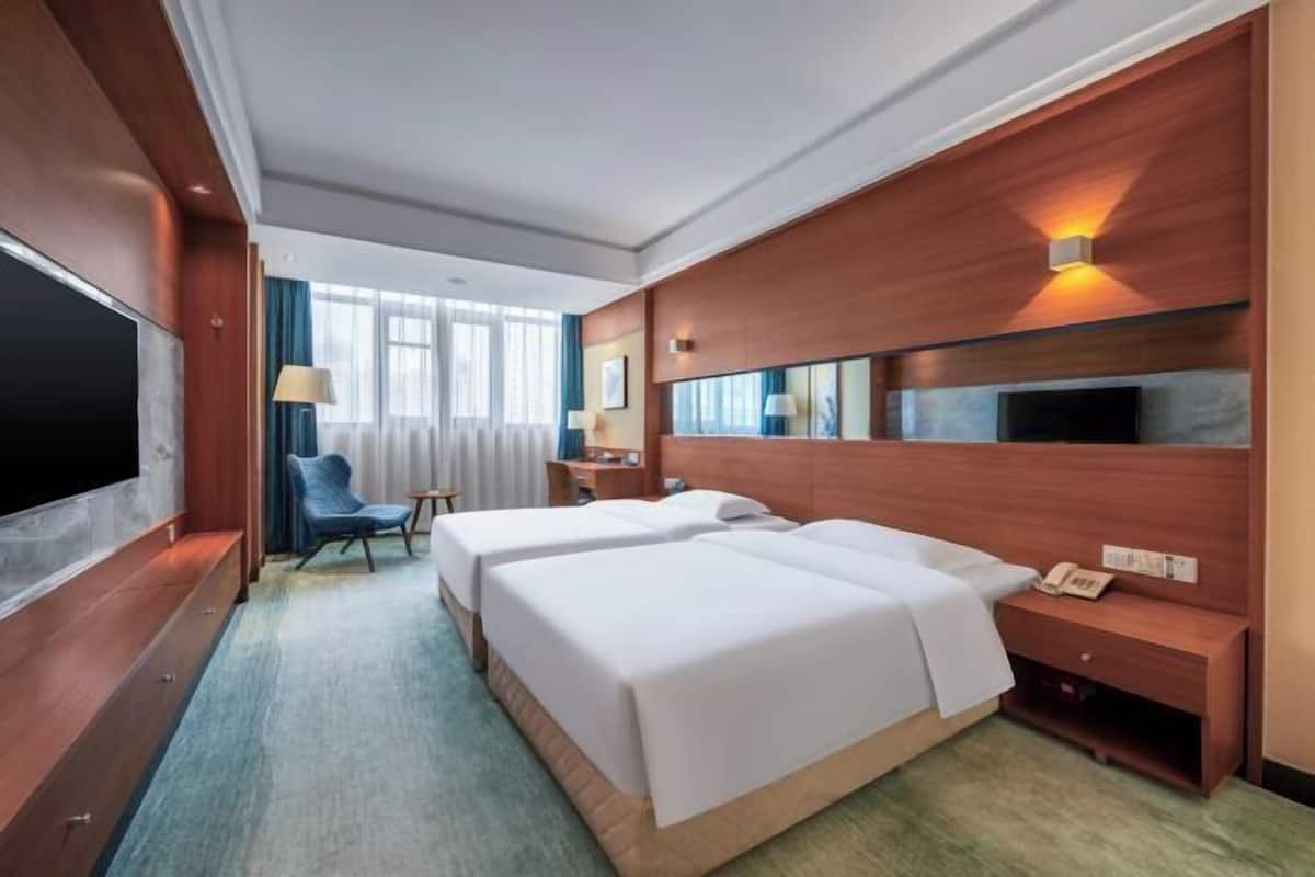Une chambre d’hôtel avec deux lits, une télévision, un bureau et une chaise.