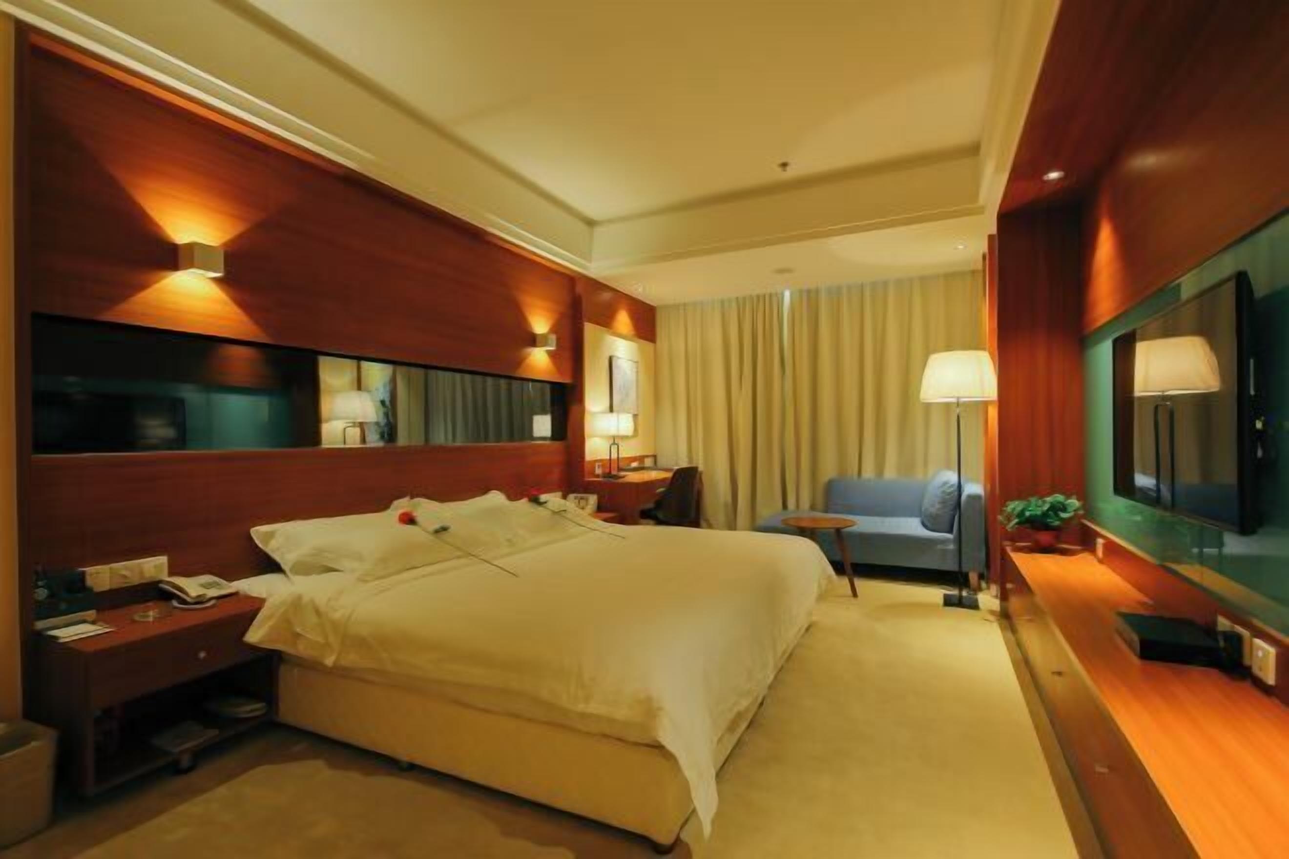 Una habitación de hotel con una cama grande, televisión, escritorio y una silla.