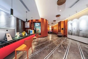 Vestíbulo de hotel con recepción, zona de estar y una gran pared con un mural.