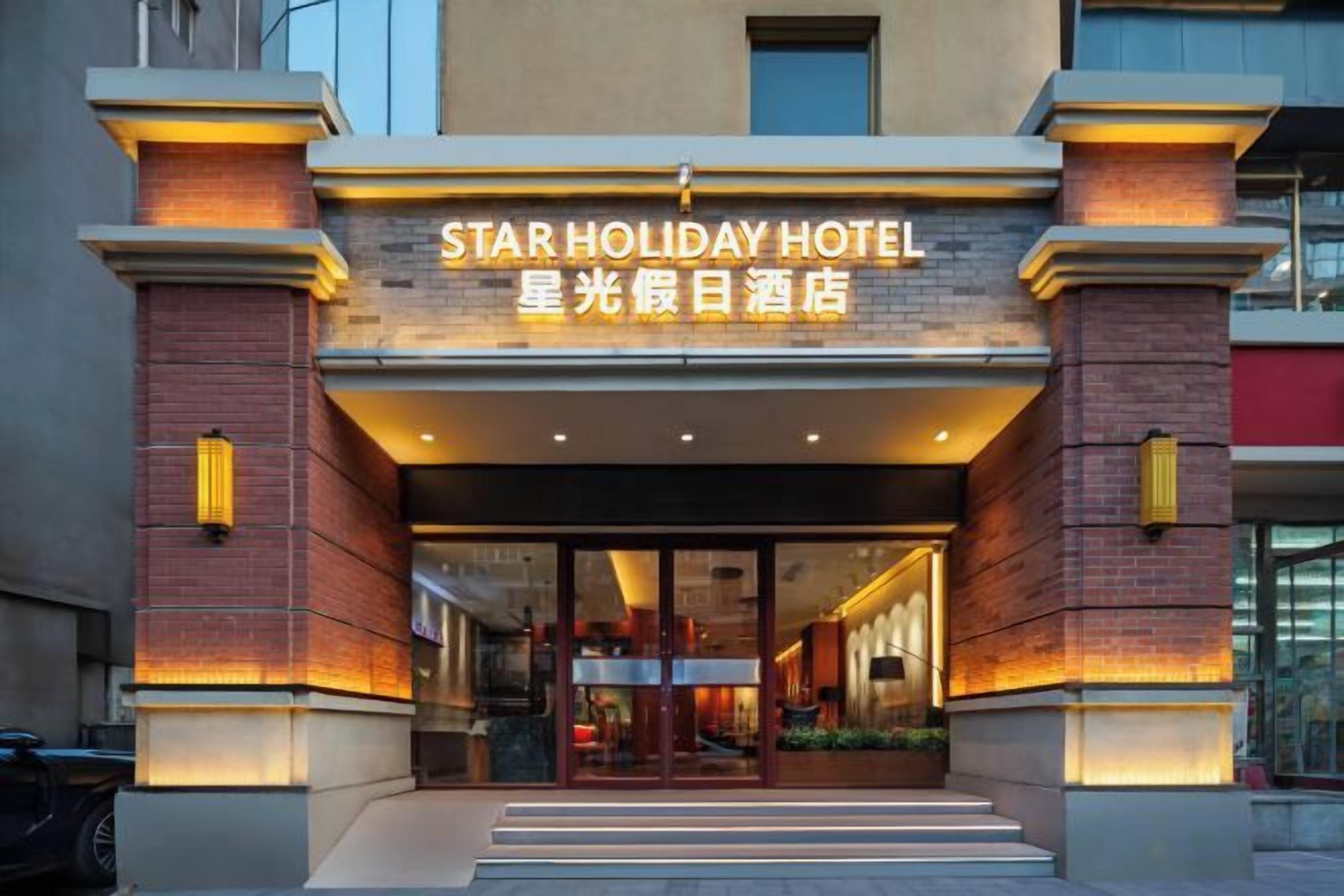 The exterior of the Star Holiday Hotel with a prominent entrance, brick facade, and illuminated signage.