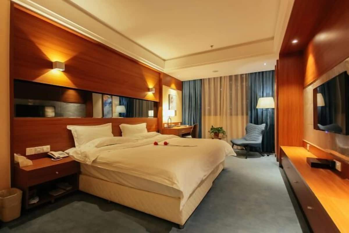 Une chambre d’hôtel avec un grand lit, des tables de chevet, une télévision et un coin salon comprenant une chaise et une petite table.