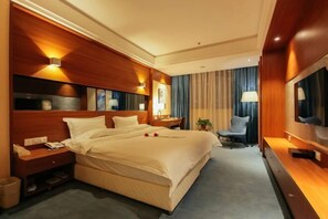 Une chambre d’hôtel avec un grand lit, des tables de chevet, une télévision et un coin salon comprenant une chaise et une petite table.