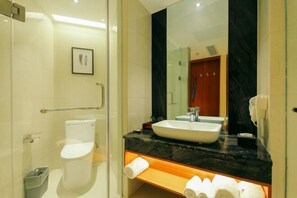 A modern bathroom with a glass shower enclosure, a white toilet, a large mirror, and a black marble countertop. - Starlight Holiday Hotel (Zhengzhou Erqi Square Dongda Street Subway Station Branch) (Zhengzhou)