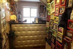 Ein Zimmer mit einer geblümten Kopfteil, einem großen Fenster und einer Wand mit gerahmten Bildern.
