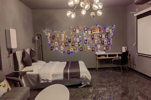 A hotel room with a bed, a desk, and a chair. There are picture frames on the wall and a chandelier above the desk. - Mizilan Zhengzhou Hotel (Guomao 360) (Zhengzhou)