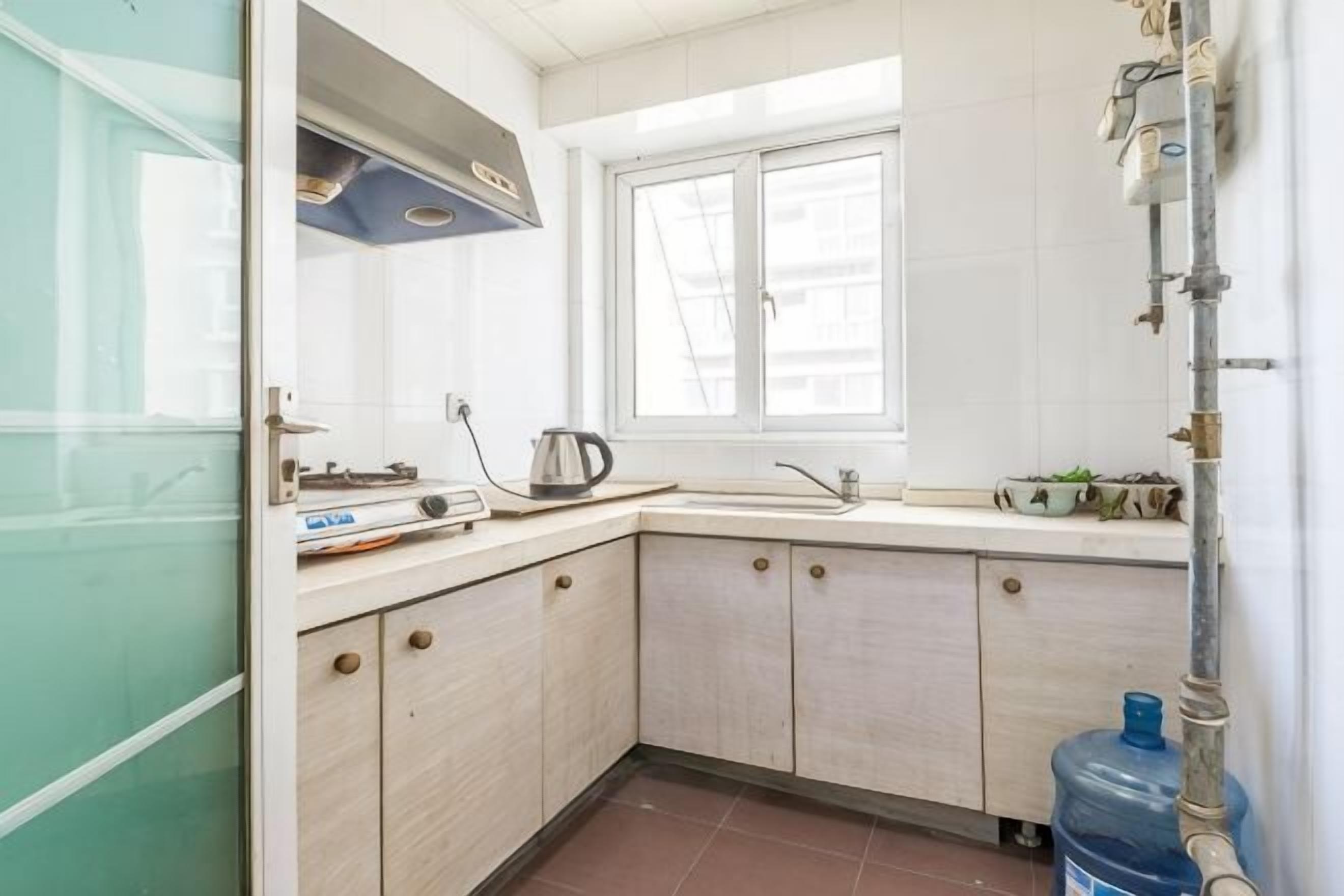 Eine Küche mit Fenster, Spüle, Schränken, Herd und Wasserspender.
