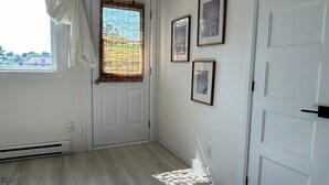 Ein Zimmer mit einem großen Fenster, einer Tür und drei gerahmten Bildern an der Wand.
