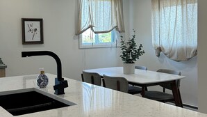 Eine moderne Küche mit einer weißen Marmorarbeitsplatte, einem schwarzen Wasserhahn und einem Fenster mit Vorhängen.