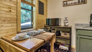 A wooden cabin interior with a dining table set for four, a microwave, and a coffee maker.