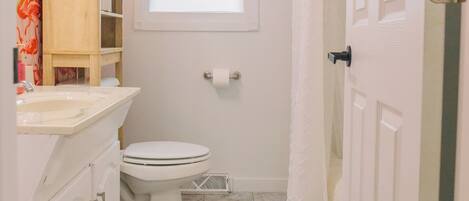 A small bathroom with a toilet, sink, and shower curtain.