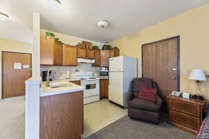 A compact kitchen with wooden cabinets, a refrigerator, a stove, and a sink.