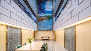 A modern interior with a central mural, a dining area with a table and chairs, and a sofa. - Biz Boutique Hotel (Hangzhou)