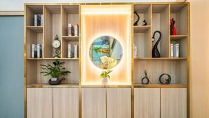 A wooden bookshelf with multiple shelves, a central circular mirror, and a potted plant. - Biz Boutique Hotel (Hangzhou)