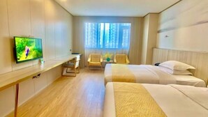 A hotel room with two beds, a desk with a TV, a window with curtains, and a view of buildings outside. - Biz Boutique Hotel (Hangzhou)