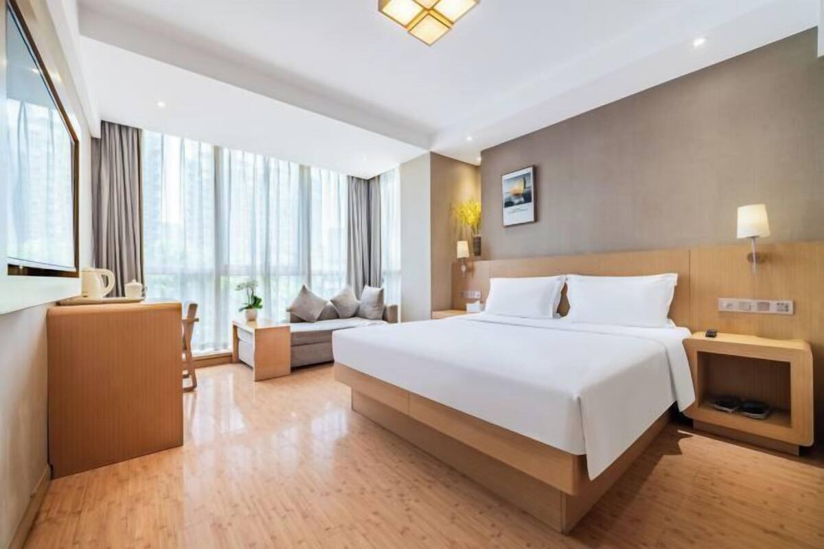 Une chambre d’hôtel moderne, dotée d’un grand lit, d’un bureau, d’une chaise et d’une fenêtre avec des rideaux.