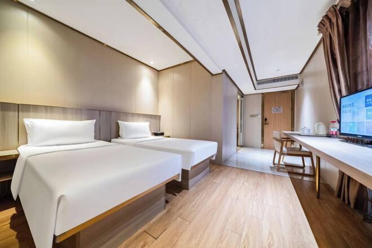Une chambre d’hôtel avec deux lits, un bureau et une télévision.