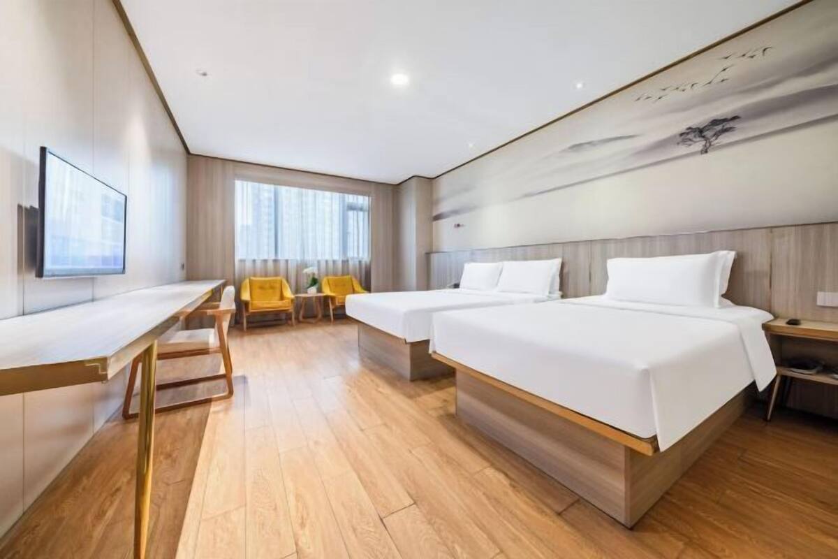 Une chambre d’hôtel avec un lit, un bureau, une chaise et une grande fenêtre.