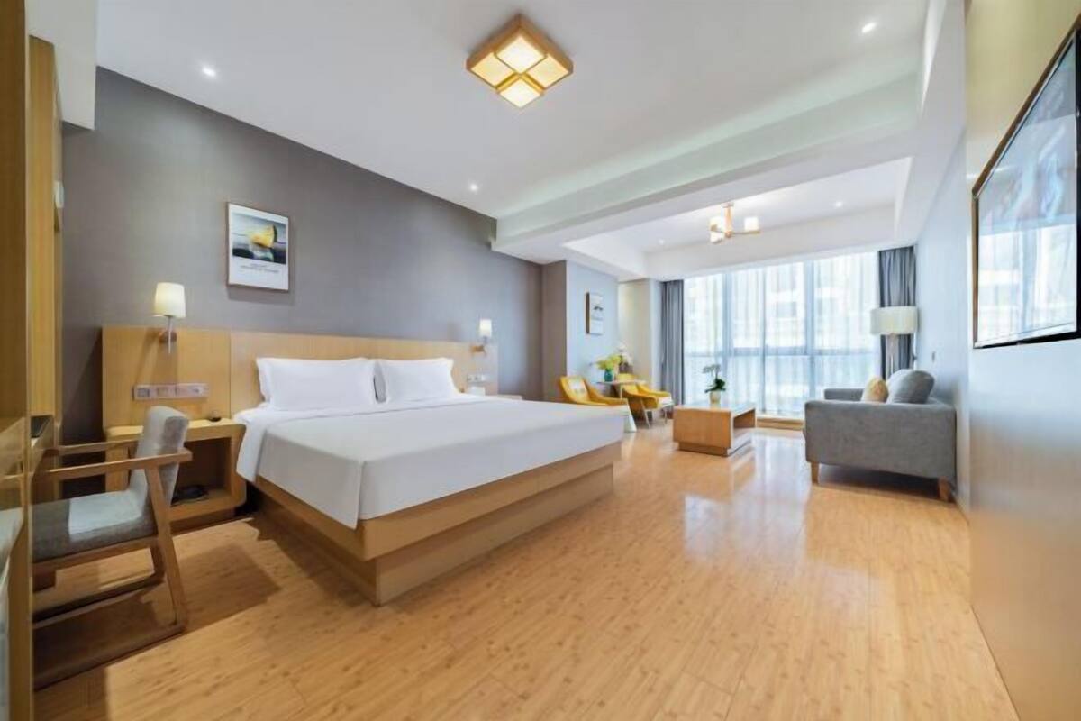 Une chambre d’hôtel moderne, dotée d’un grand lit, d’un bureau, d’une chaise, d’un canapé et d’une grande fenêtre.