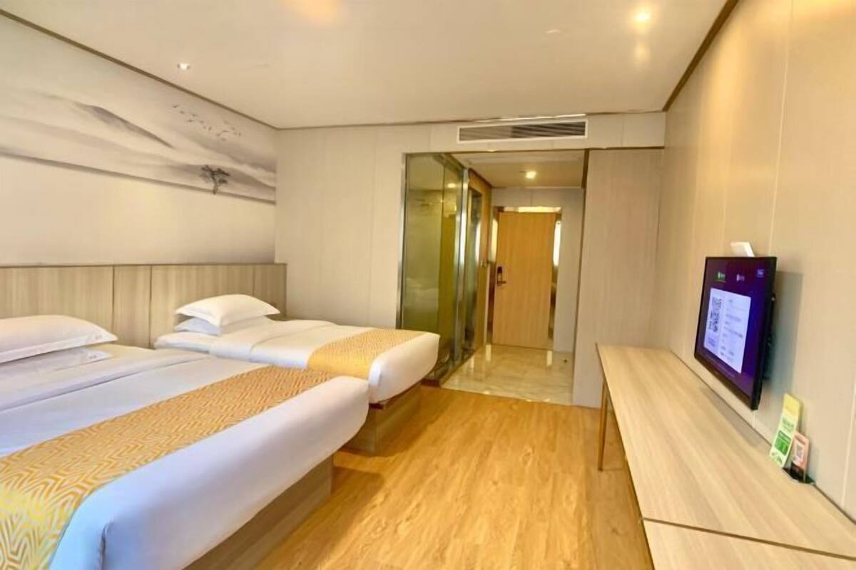 Une chambre d’hôtel avec deux lits, une télévision et un plancher en bois.