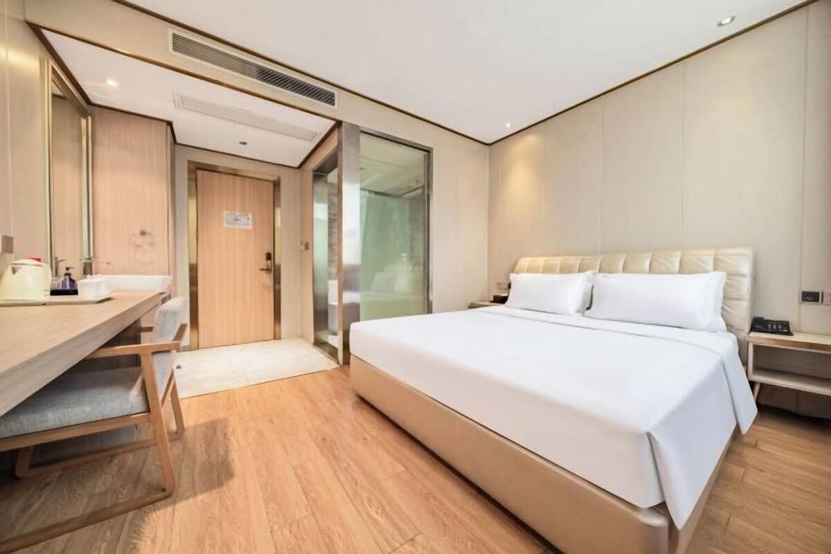 Une chambre d’hôtel moderne, dotée d’un grand lit, d’un bureau et d’un miroir.