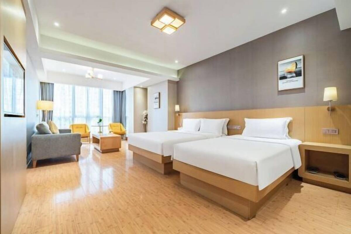 Une chambre d’hôtel avec deux lits, un canapé, un bureau et une vue sur la ville.