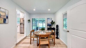 Un comedor con una mesa redonda, cuatro sillas y vista a la cocina a través de puertas de cristal.