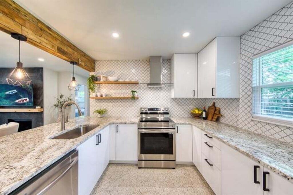 A modern kitchen with white cabinets, a stainless steel oven, and a granite countertop.