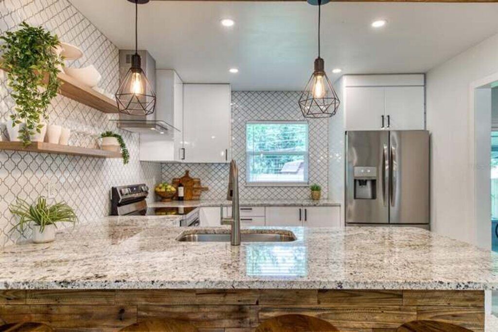 Una cocina moderna con encimeras de granito, electrodomésticos de acero inoxidable e iluminación colgante.