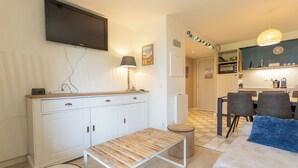 A modern living room with a sofa, a coffee table, and a TV mounted on the wall. - Appt 2 pièces cabine 6 pers avec piscine, tennis, parking gratuit 157 (Le Touquet-Paris-Plage)