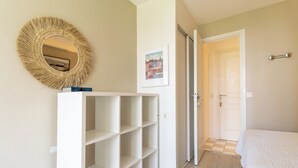 A bedroom with a bed, a white wardrobe, a mirror, and a door leading to another room. - Appt 2 pièces cabine 6 pers avec piscine, tennis, parking gratuit 157 (Le Touquet-Paris-Plage)