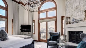 Ein geräumiges Schlafzimmer mit einem großen Bett, einem Fernseher und einem Kamin.