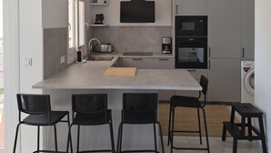 Una cocina moderna con una isla central, taburetes de bar y electrodomésticos integrados.