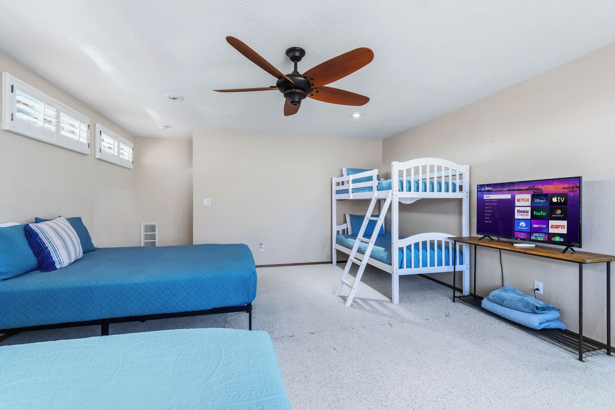 Une chambre avec des lits superposés, un lit simple, un ventilateur de plafond et un téléviseur permettant d’accéder à des services de diffusion en continu.