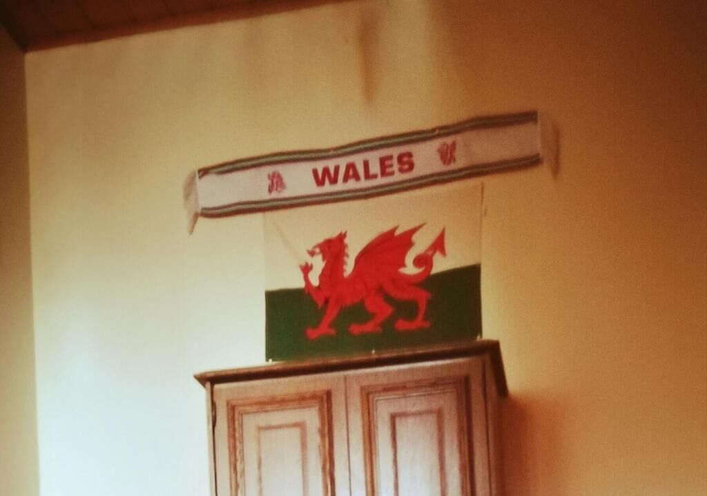 Un letrero con un dragón rojo y la palabra 'WALES' en una pared.