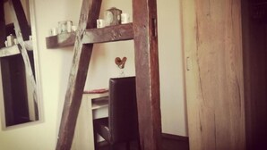 A room with exposed wooden beams, a desk with a chair, and a wooden door. - Henblas-Hotel (Neuenrade)