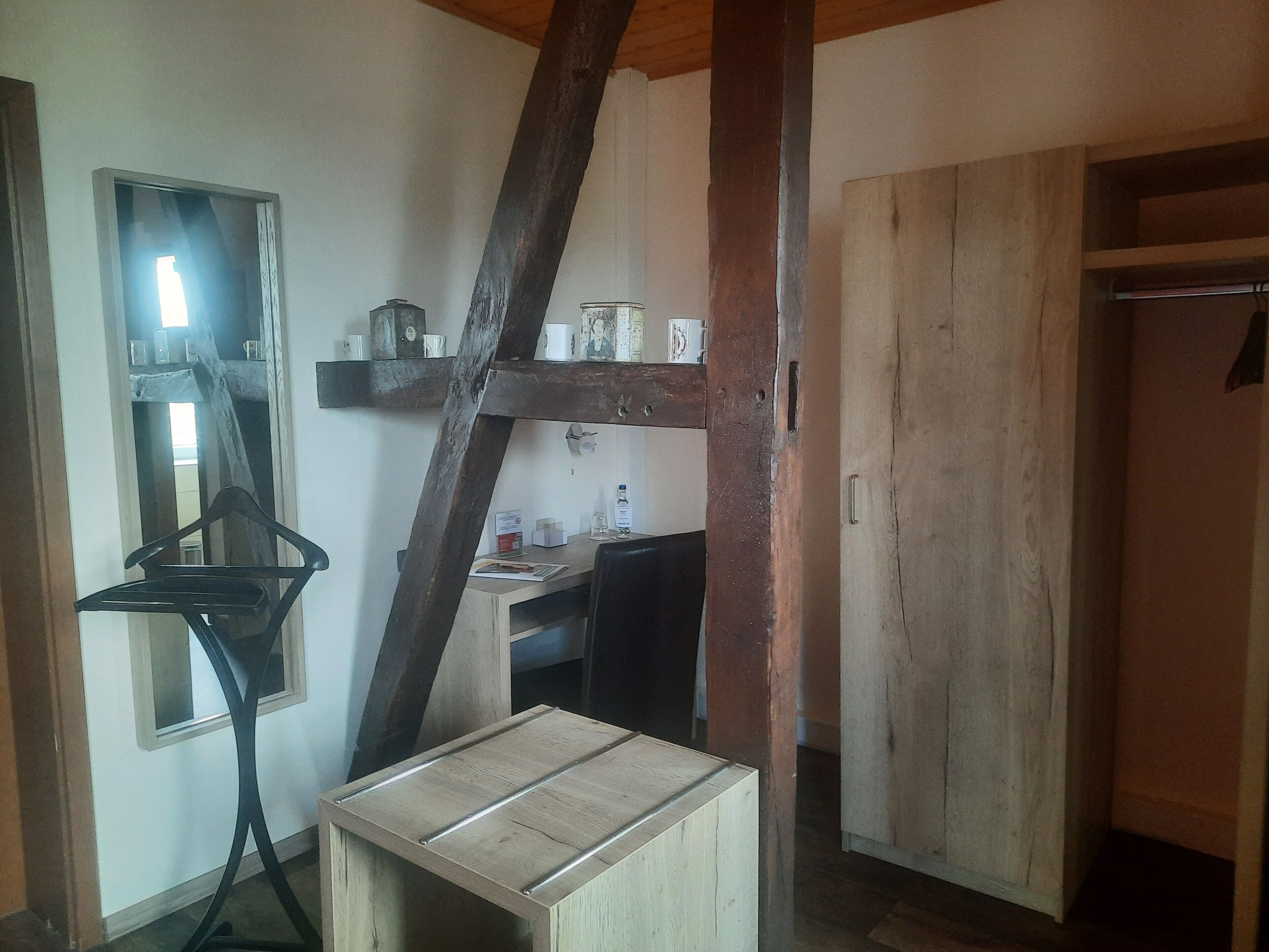 Une pièce rustique avec une table en bois, une chaise suspendue, un miroir et une armoire en bois.