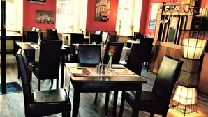 A restaurant with tables and chairs, wooden floors, and wall-mounted artwork. - Henblas-Hotel (Neuenrade)