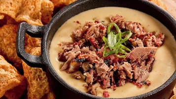 A bowl of soup with meat garnish, surrounded by tortilla chips.