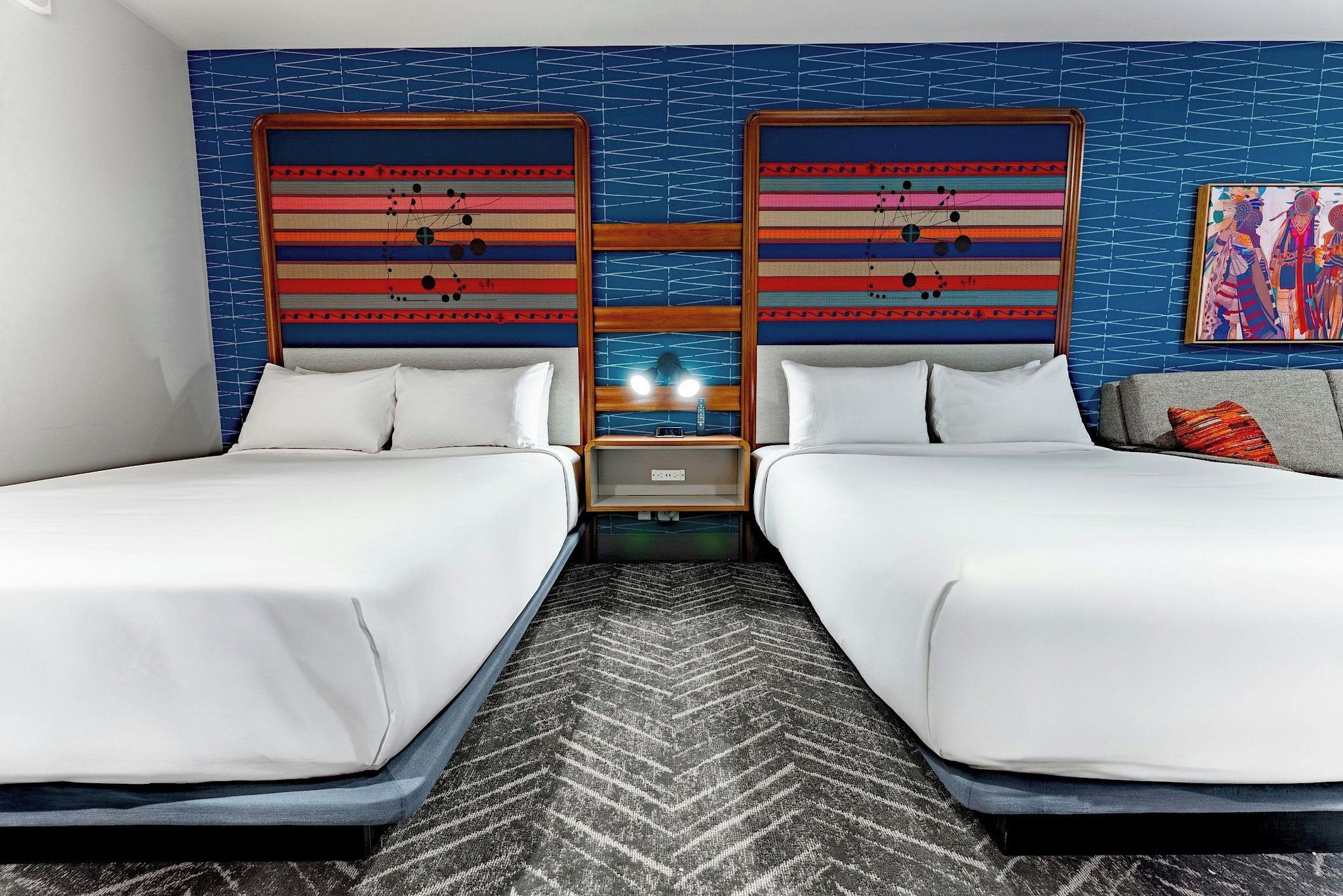 Ein Hotelzimmer mit zwei Betten, einem Nachttisch und einem an der Wand befestigten Fernseher.