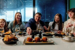 A group of people dining at a table with various dishes and glasses of wine. - OKANA Resort & Indoor Waterpark (Oklahoma City)