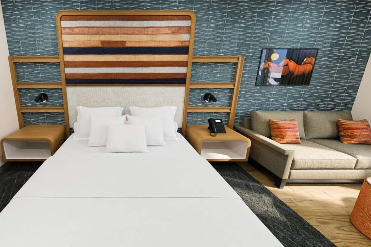 Ein modernes Hotelzimmer mit einem langen Bett, einer Couch, einem Couchtisch und einem Fernseher an der Wand.
