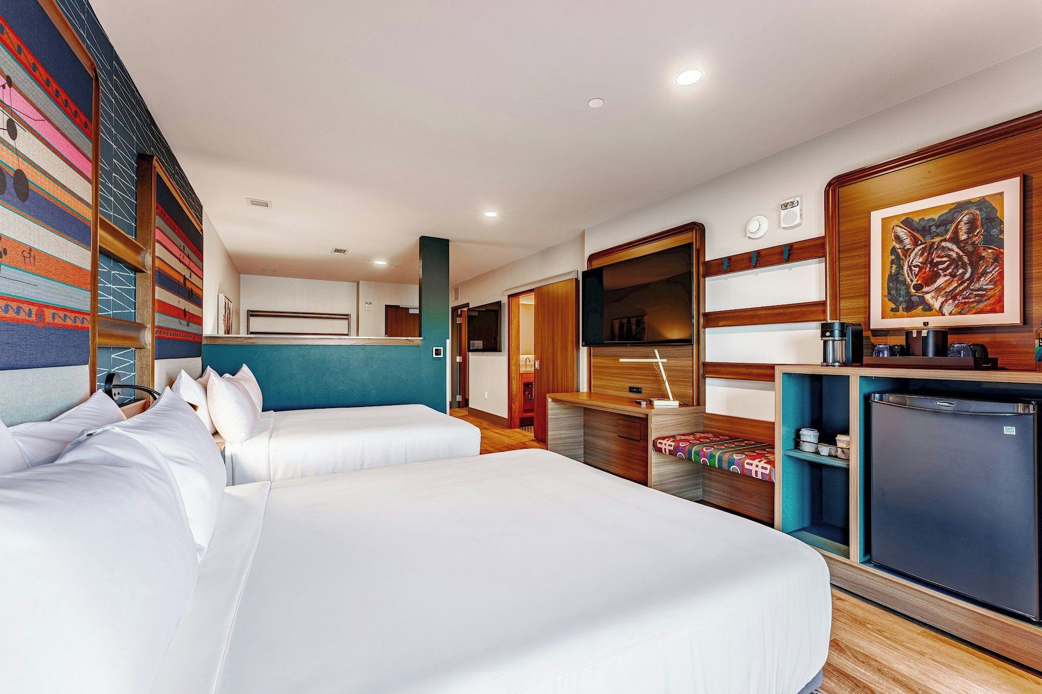 Een hotelkamer met twee bedden, een kitchenette, een badkamer en een groot raam.