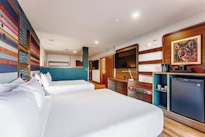 Ein Hotelzimmer mit zwei Betten, einer Küchenzeile, einem Badezimmer und einem großen Fenster.