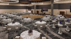 Banquet hall with round tables, chandeliers, and a stage area.