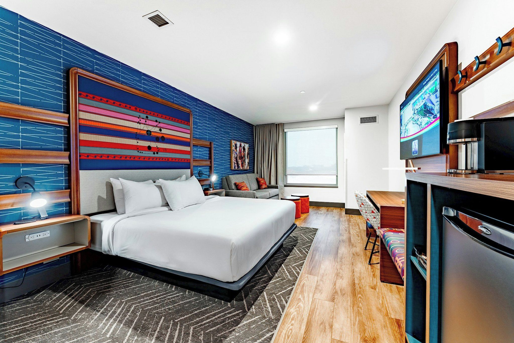 Une chambre d’hôtel moderne équipée d’un grand lit, d’un bureau, d’une télévision et d’un mini-bar.