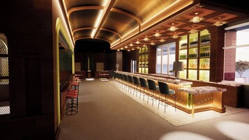 A bar area with a long counter, bar stools, and shelves with bottles.