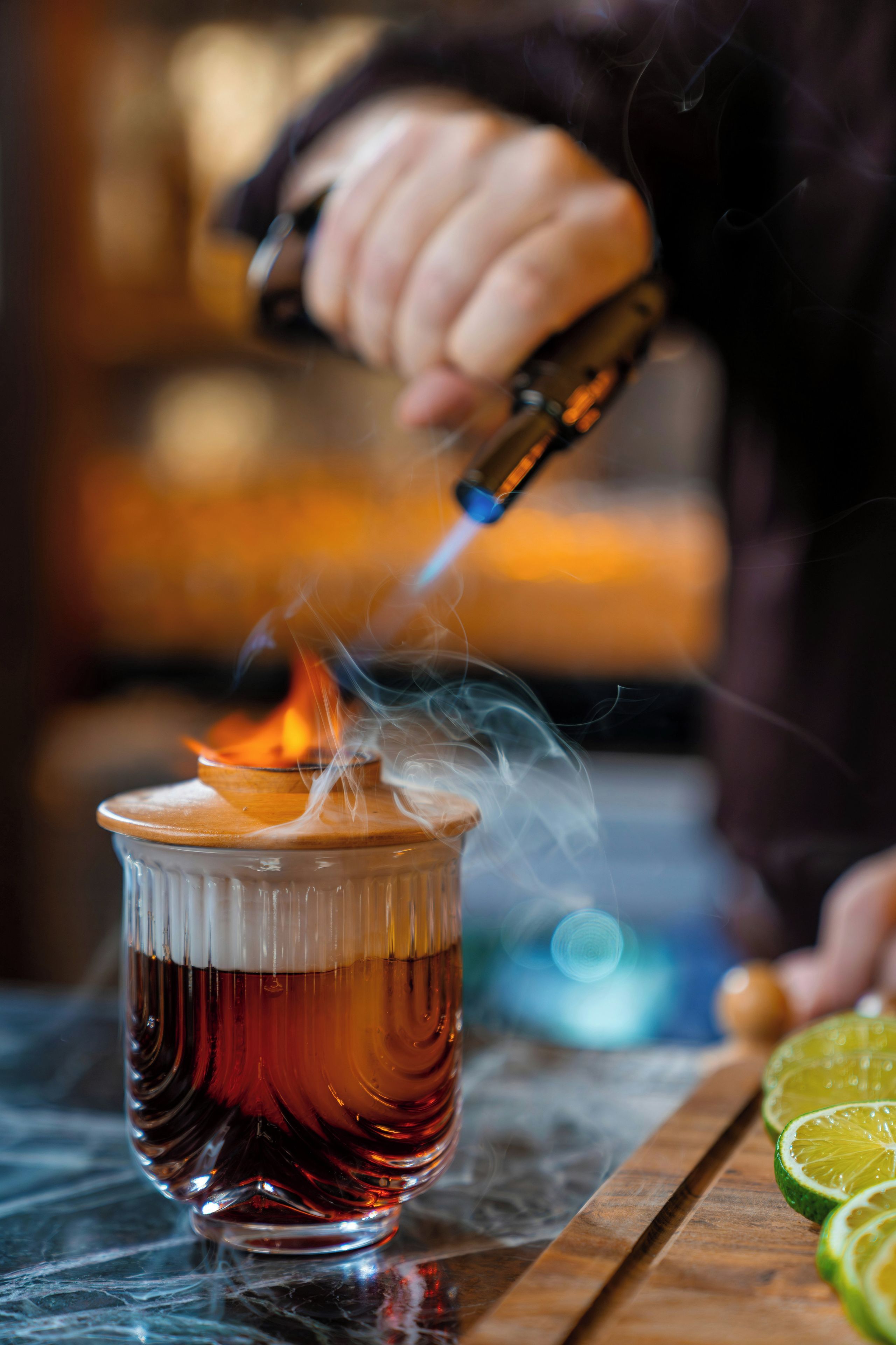 A hand pouring a liquid from a bottle into a glass, creating a flame.