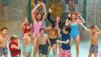 A group of people playing in a water feature with a wooden design.