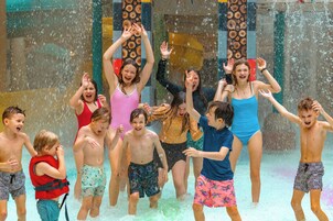 A group of people playing in a water feature with a wooden design.