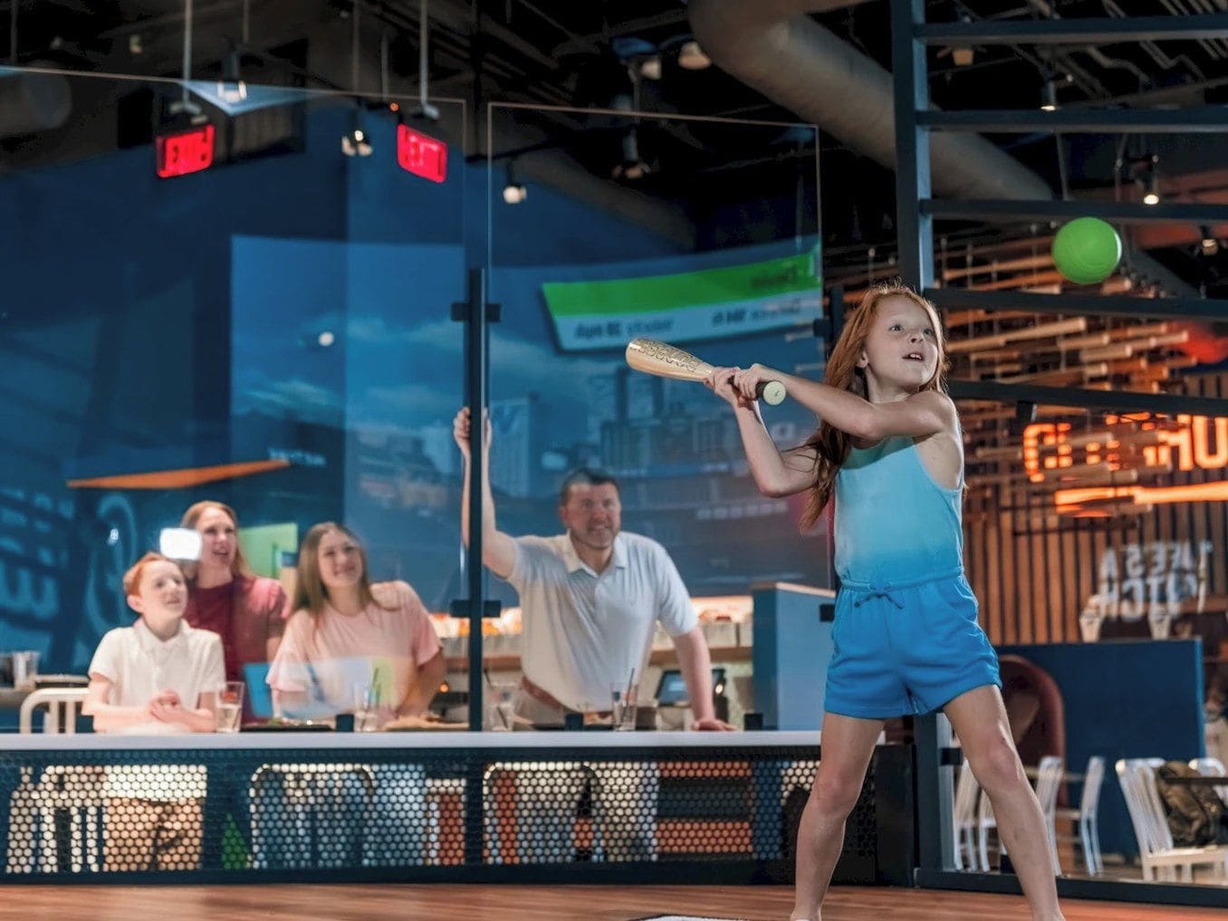 A person playing a sport, possibly baseball, in an indoor setting with spectators.